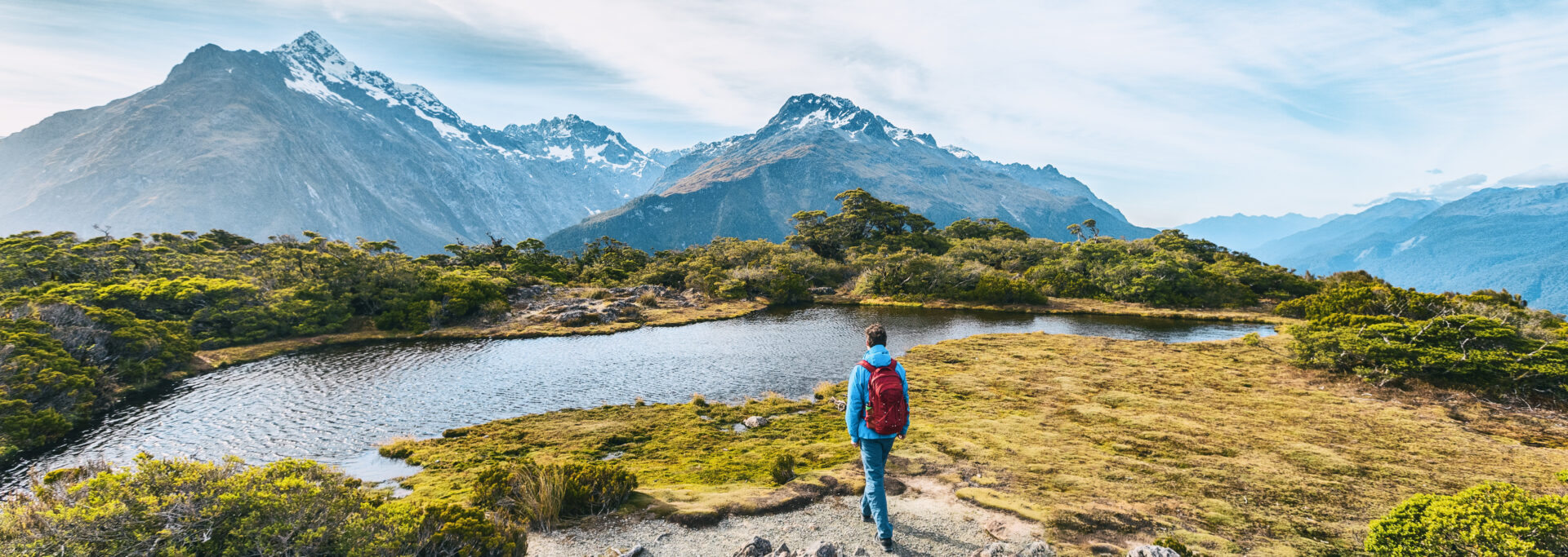 Hiking Vacations: Young hiking man walking on trail at Routeburn Track in Fiordland National Park in New Zealand. New Zealand tours