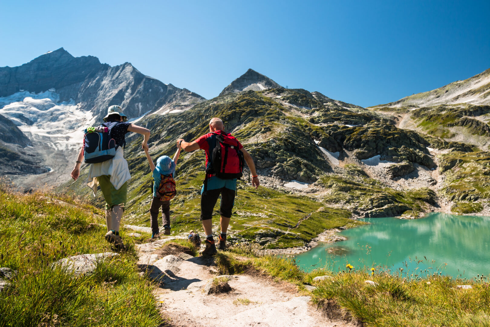 family adventure trips: family with child hiking on holiday in Austrian alps by an alpine lake