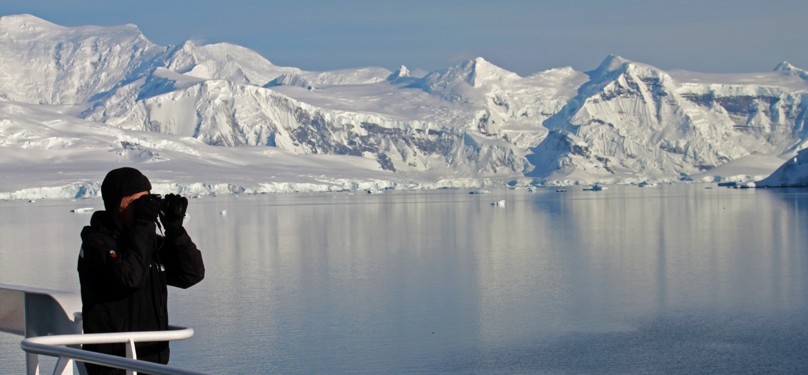 Antarctica Man looking through binoculars from the ship