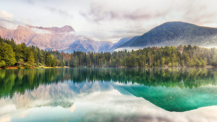 Incredible view of sunset over Fusine lake with Mangart peak on background. Popular travel destination of Julian Alps. Location: Tarvisio comune , Province of Udine, Italy, Europe